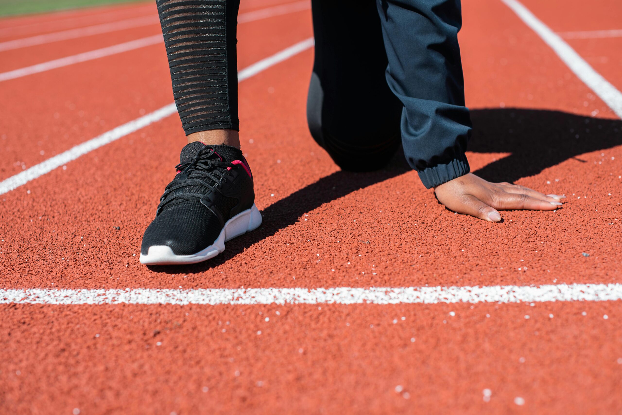 Runner in crouched starting position on track, ready to sprint.